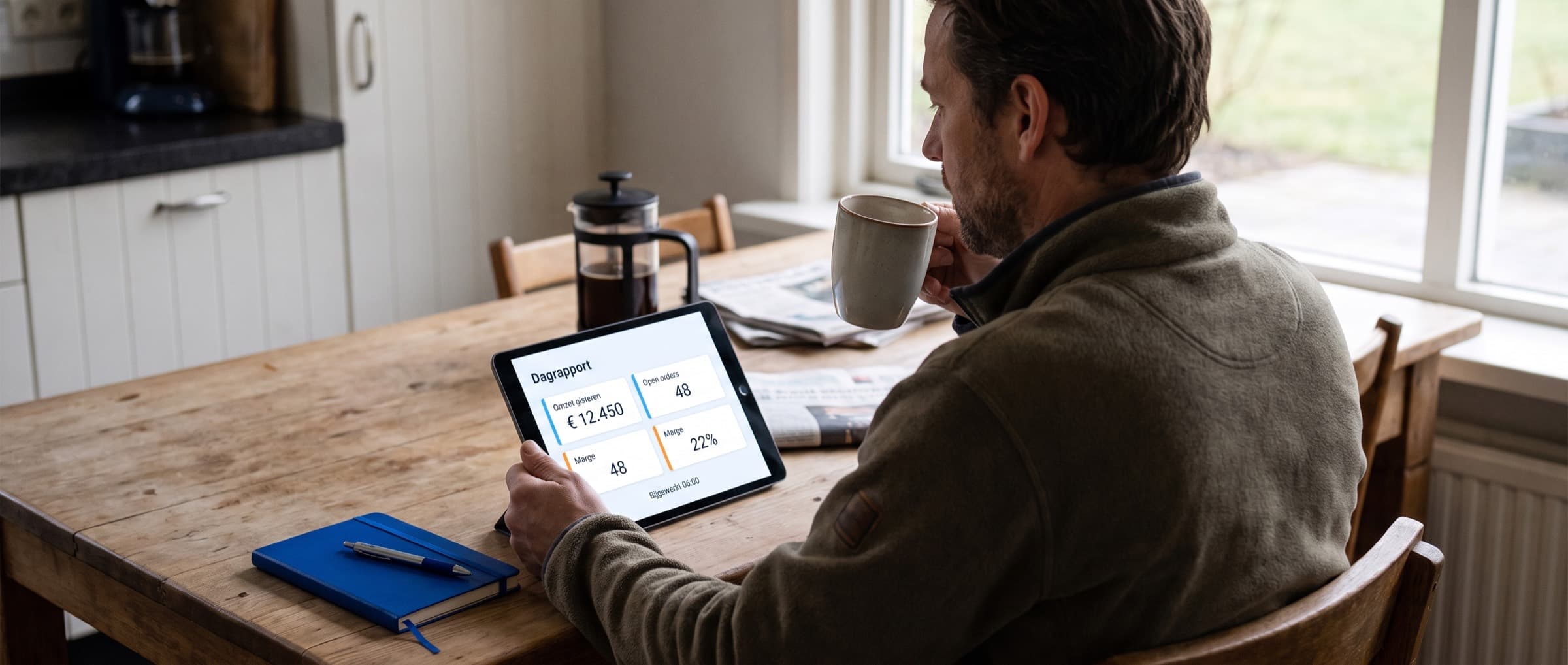 Eigenaar bekijkt aan de keukentafel op een tablet het dagrapport