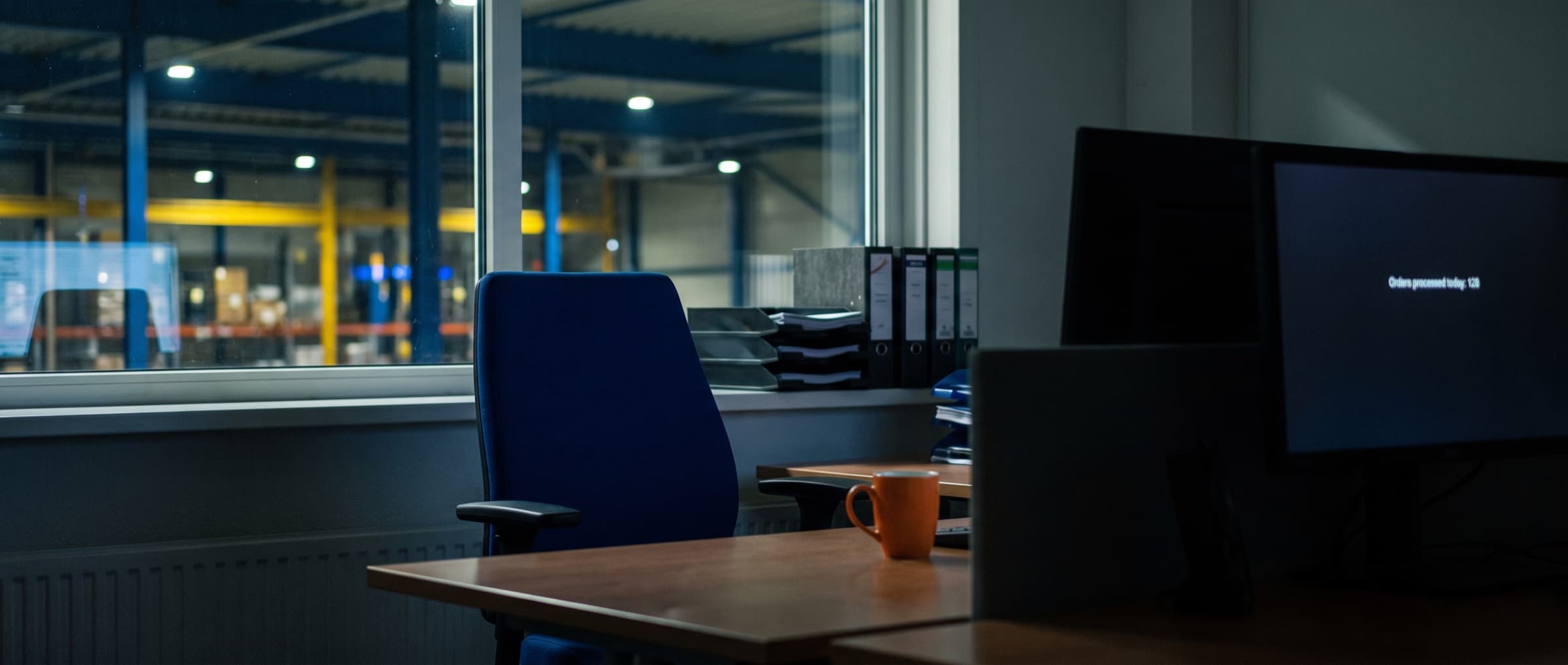 Quiet order desk at a Dutch distributor with a monitor showing a running workflow in the background