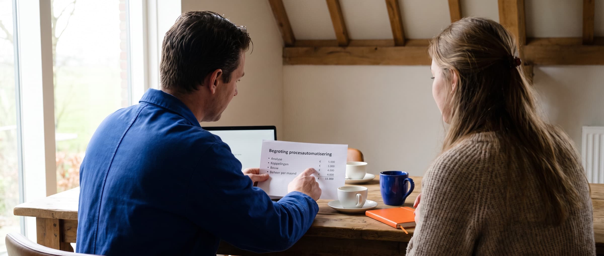 Ondernemer en bouwer bespreken een begroting aan tafel in een boerderijkantoor