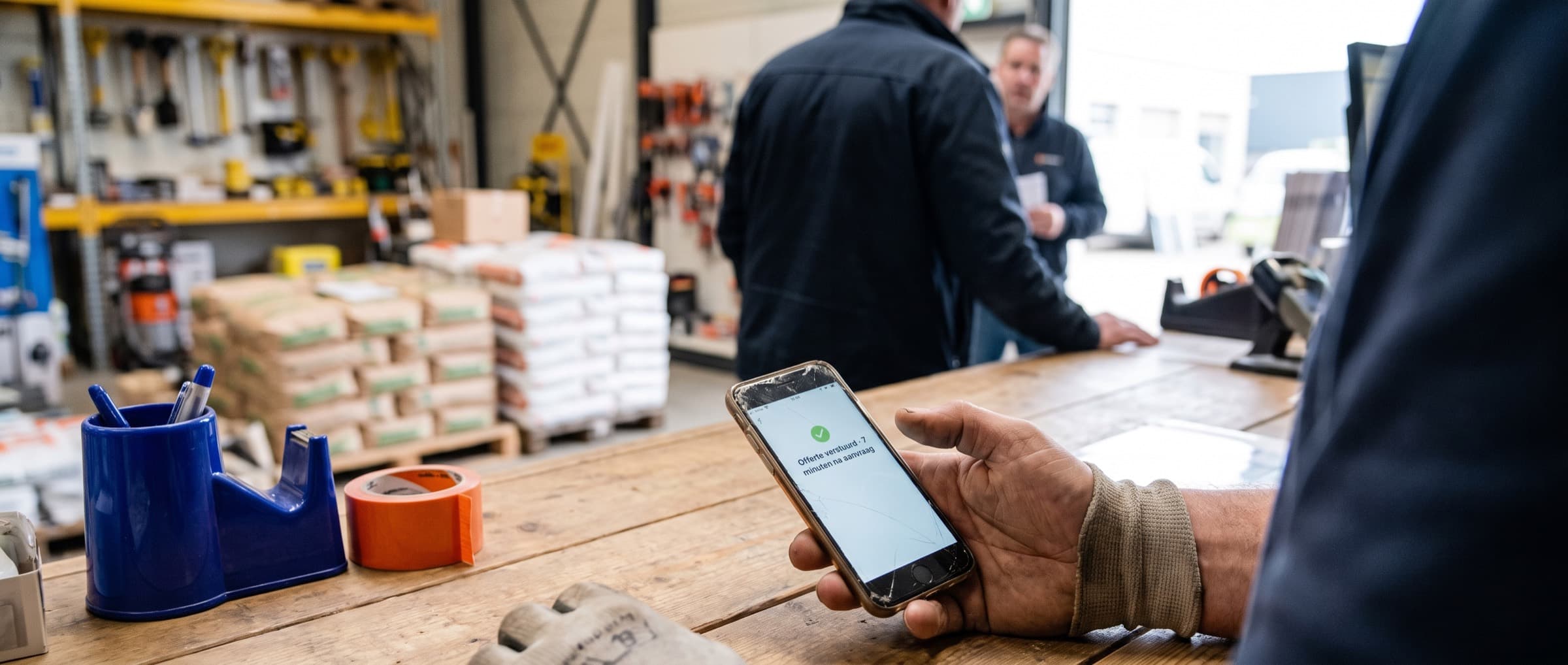 Hand met een telefoon met de melding dat een offerte binnen minuten verstuurd is