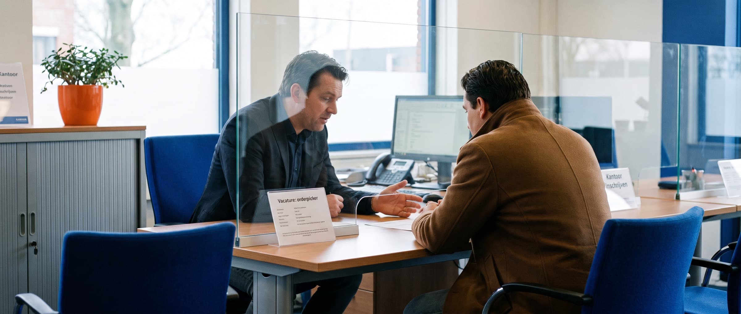 Recruiter praat met een kandidaat aan de balie van een uitzendbureau