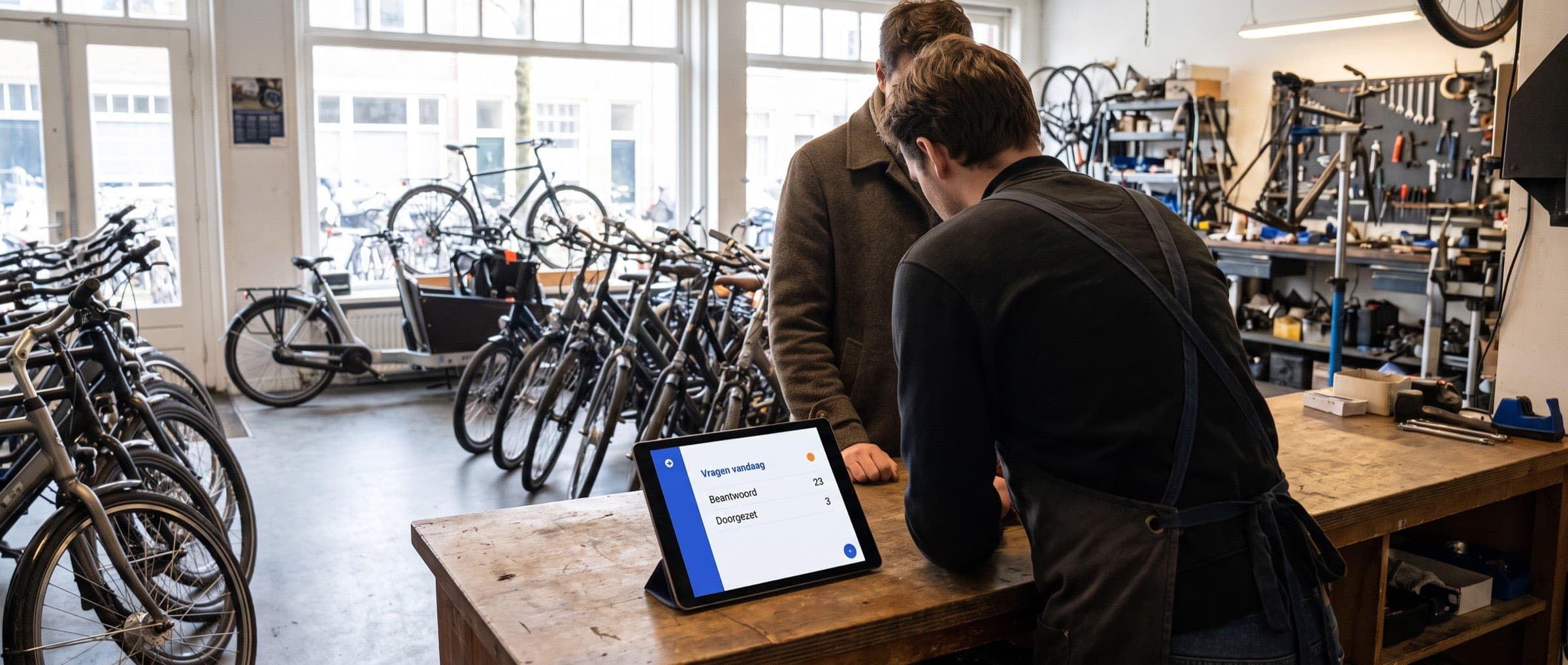Medewerker aan de balie van een fietsenwinkel helpt een klant, terwijl op een tablet naast de kassa binnenkomende vragen al zijn beantwoord
